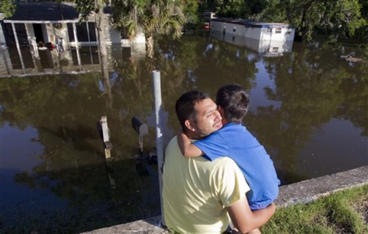 Jorge Torrez hugs his son Jayden, 12, as they sit on a wall overlooking their flooded home in Live Oak Fla., Wednesday, June 27, 2012. Dozens of homes and much of the downtown area was flooded by torrential rains from Tropical Storm Debby. (AP Photo/Dave Martin)
